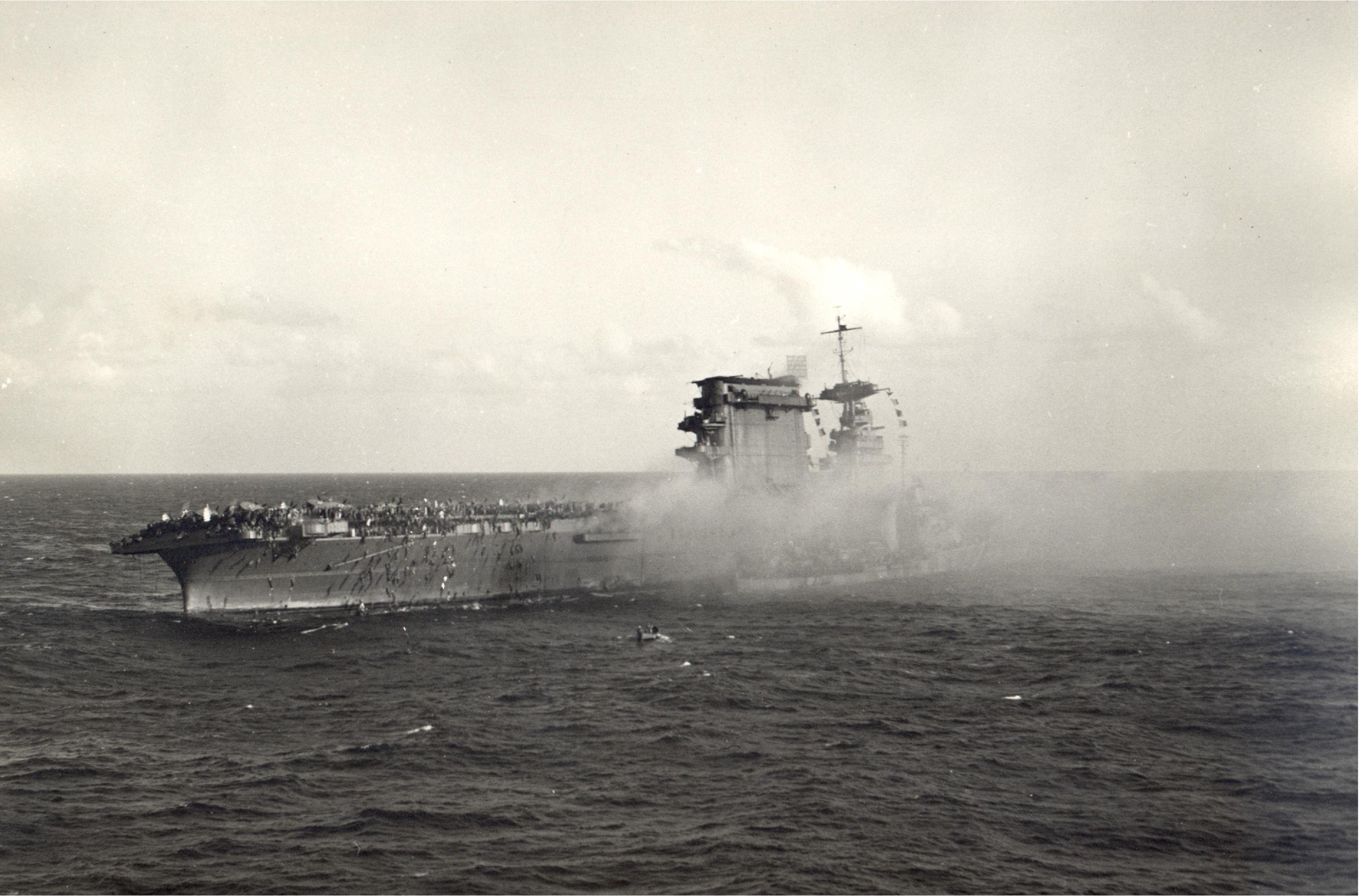 Crewmen abandon ship aboard USS Lexington (CV-2) after she was hit by Japanese torpedoes and bombs during the Battle of the Coral Sea, May 8, 1942. A destroyer is alongside taking on survivors.